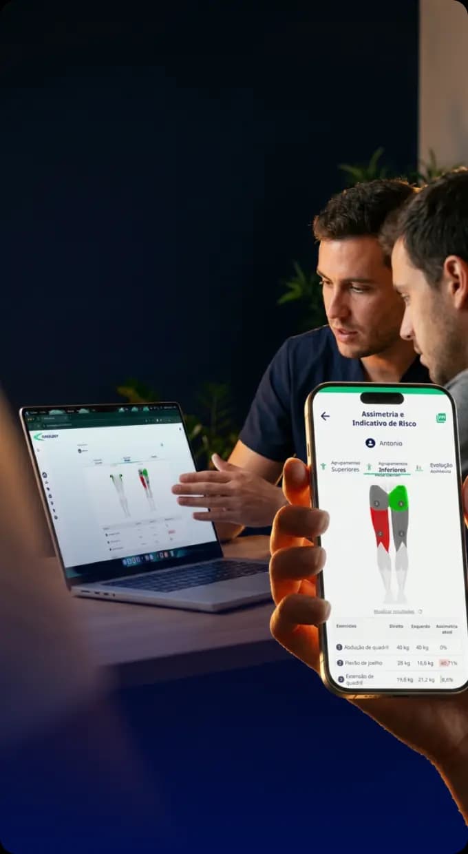 Fisioterapeuta e paciente analisando relatório de assimetria muscular no app Kinology, no laptop e no celular